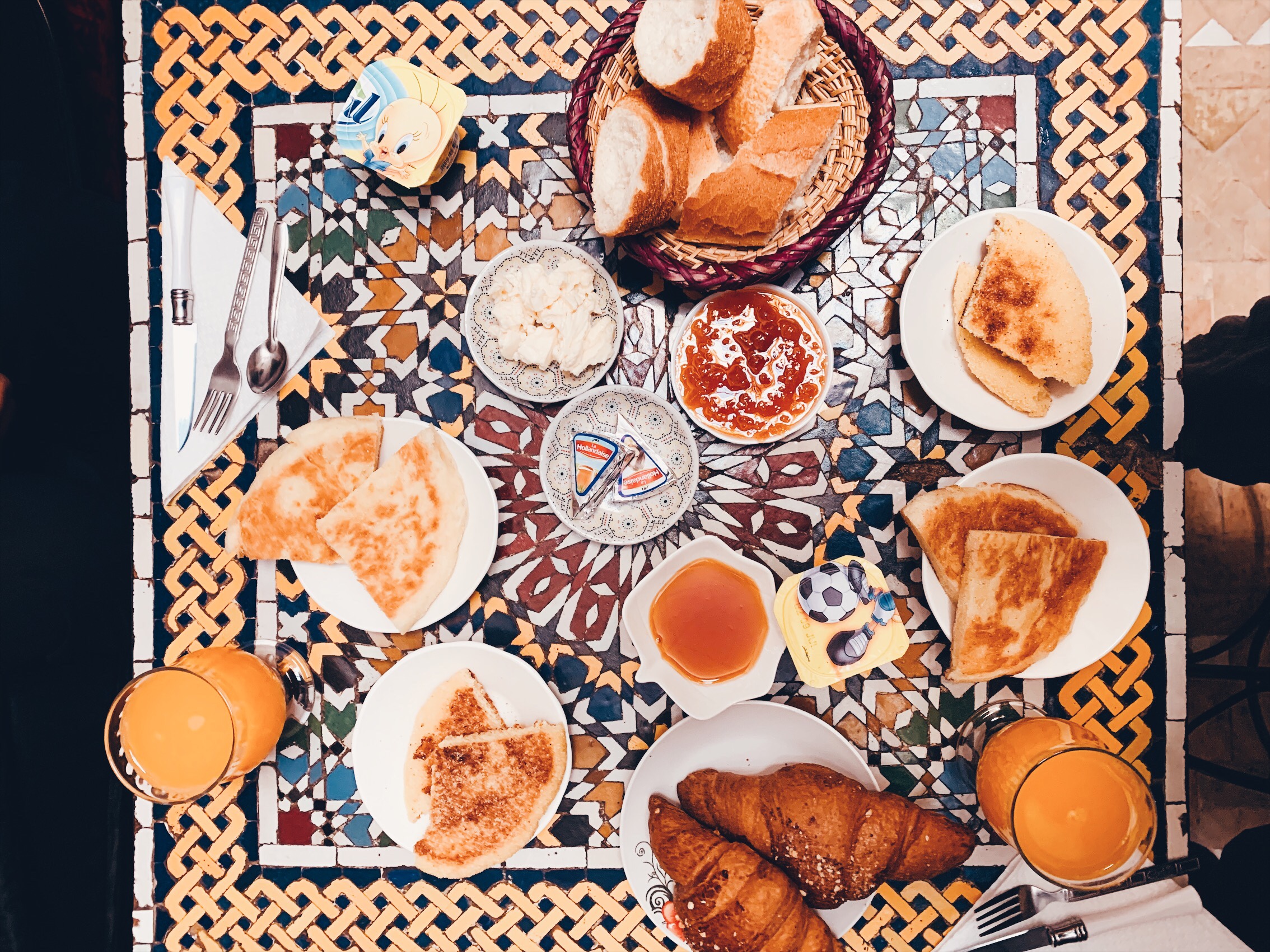 A huge breakfast is spread out on an intricate mosaic table.